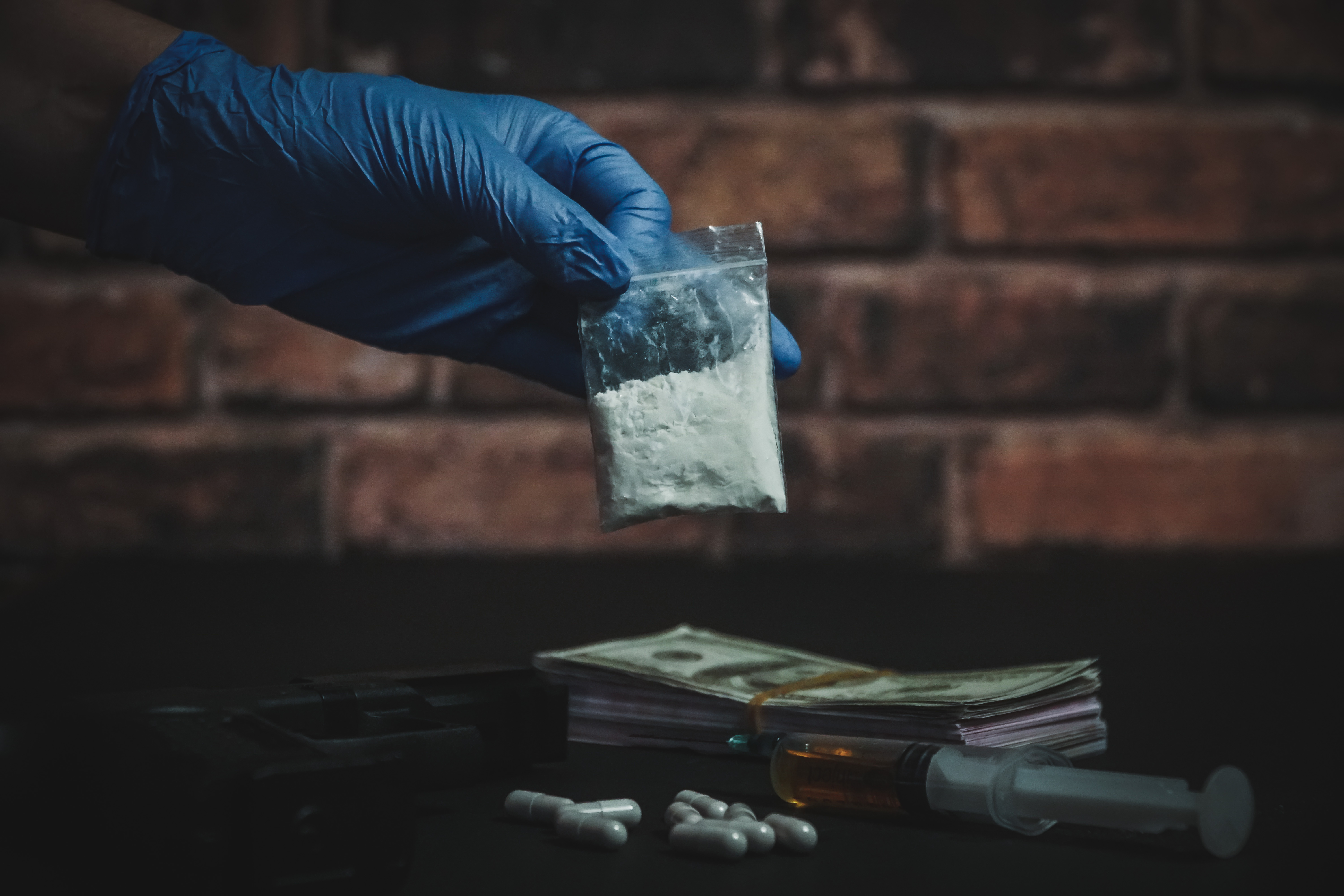 A gloved hand holding up a bag filled with a substance - Facing a drug charge? Branson West Law is an experienced drug distribution lawyer in Utah.